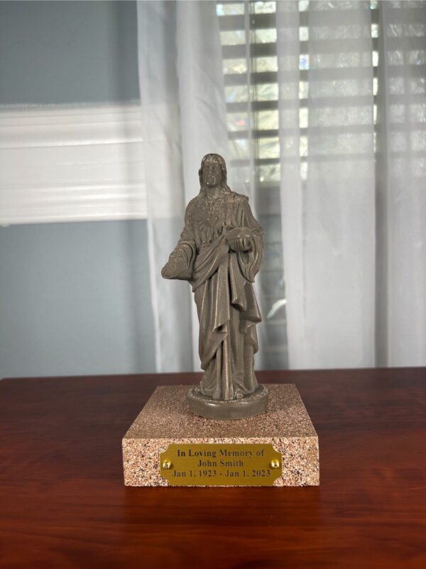 A cremation sculpture that is made from the ashes of someone who passed away. Shaped in the form of Jesus with a wooden base and an engraved plaque.